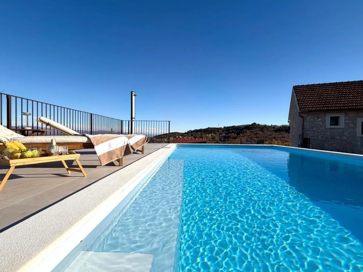 Private heated swimming pool with sun loungers and countryside views at Villa Billubium