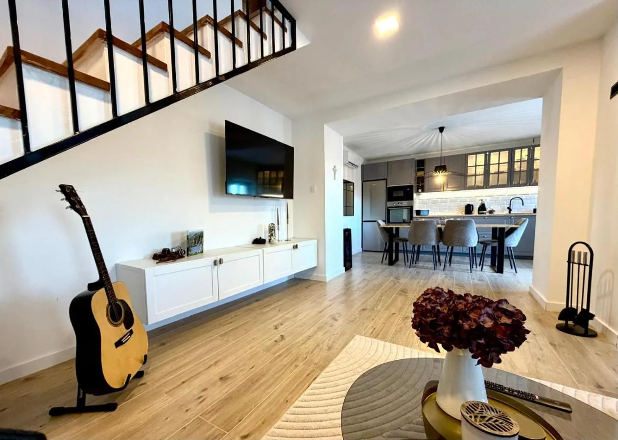 Open living room with television, guitar and kitchen beyond