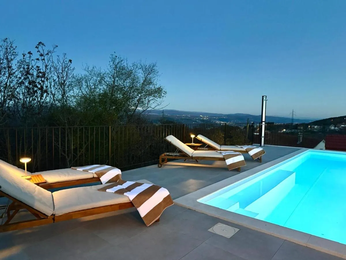 Sun loungers beside the illuminated pool at twilight